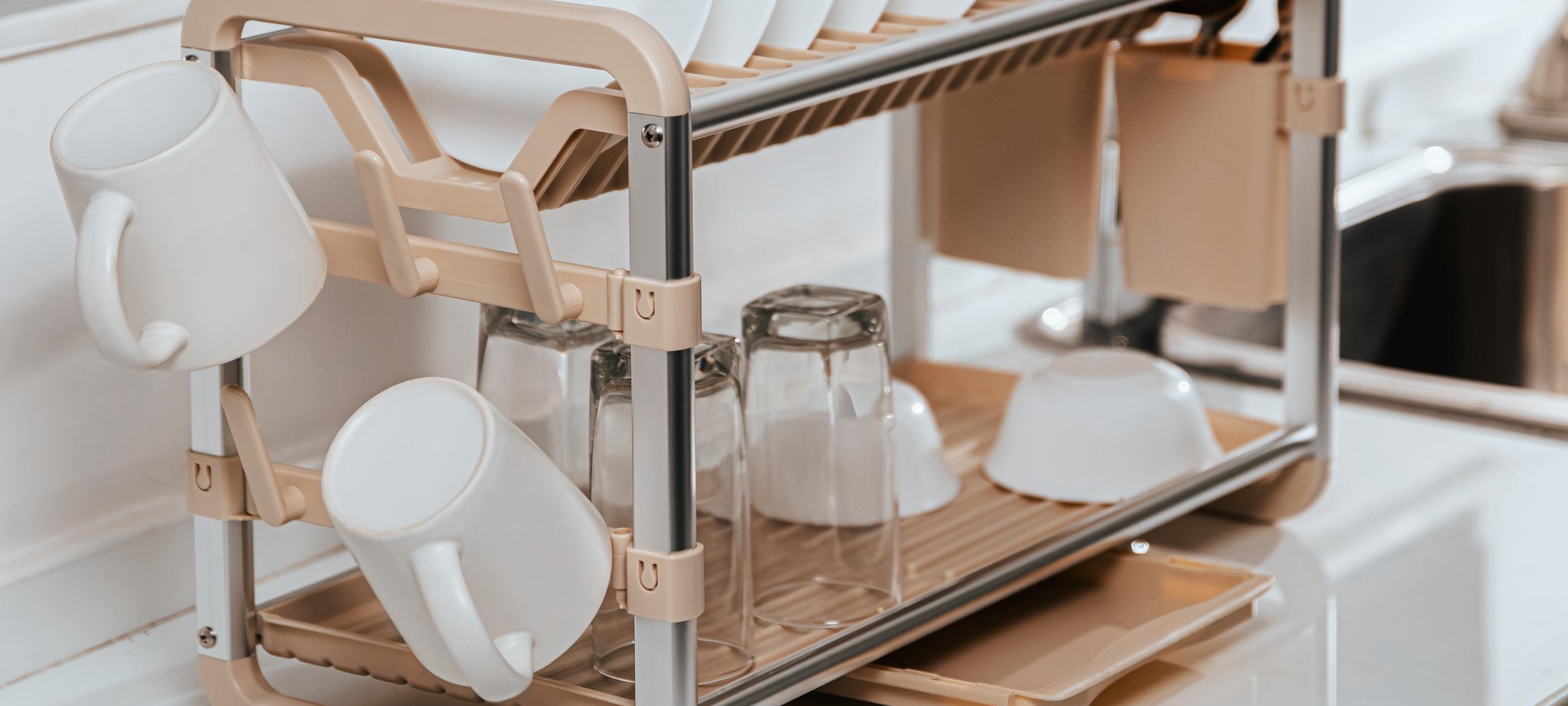 Dish rack with plates, cups, and utensils on a kitchen counter.
