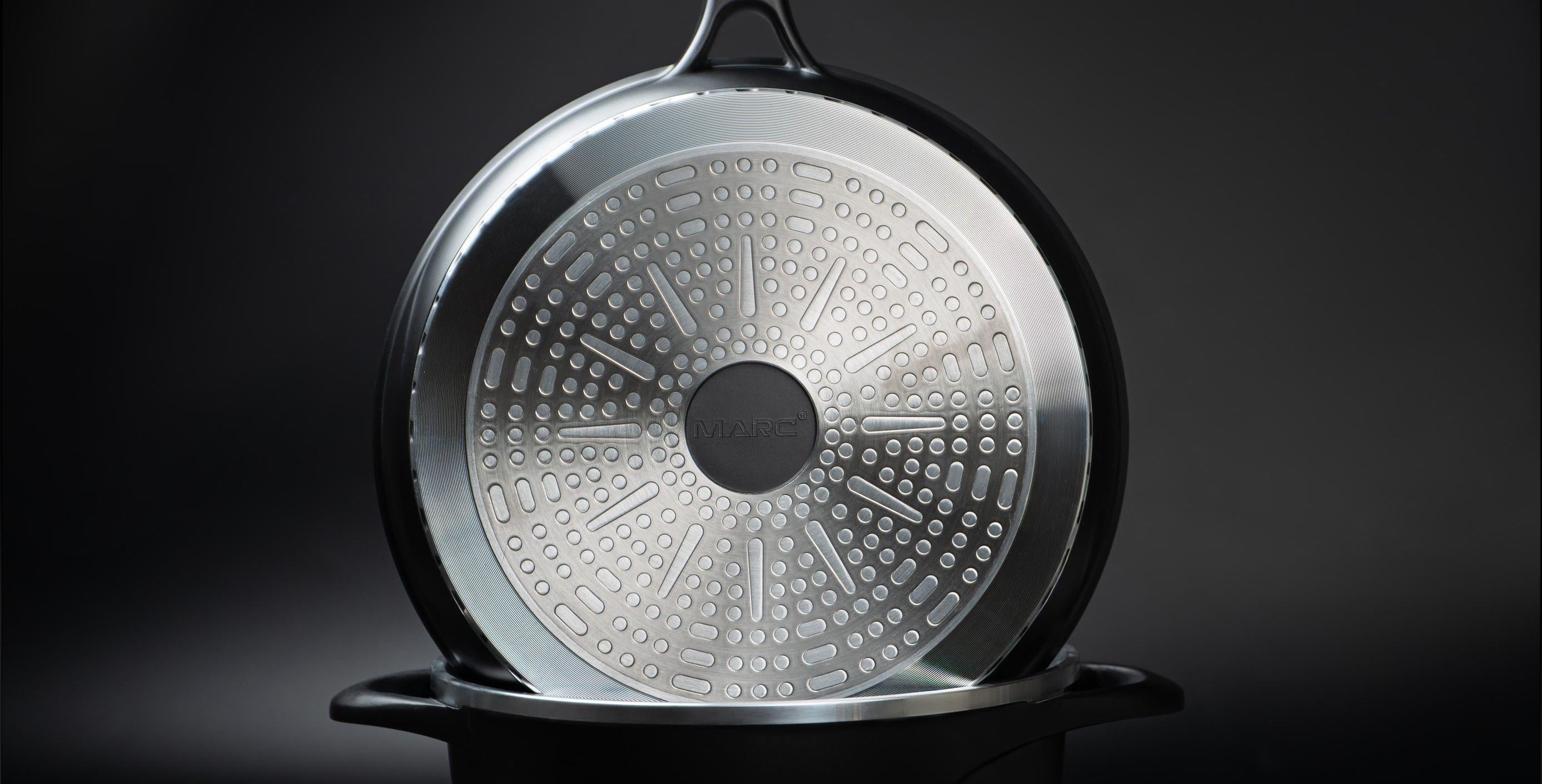 Black frying pan with a textured bottom on a dark background with peppers.